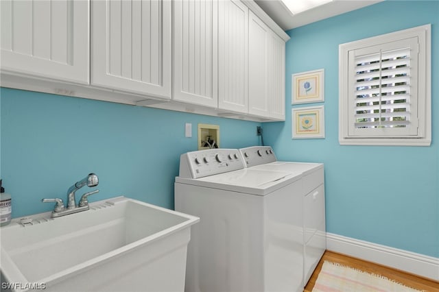 laundry room with sink, electric dryer hookup, cabinets, separate washer and dryer, and light wood-type flooring