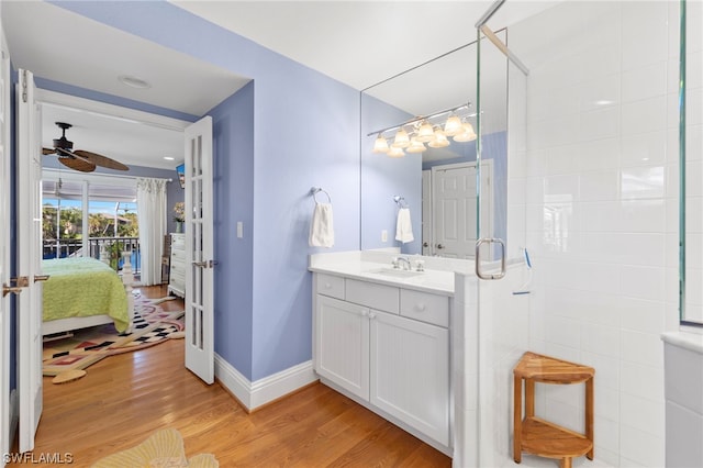 bathroom featuring hardwood / wood-style floors, ceiling fan, and vanity with extensive cabinet space