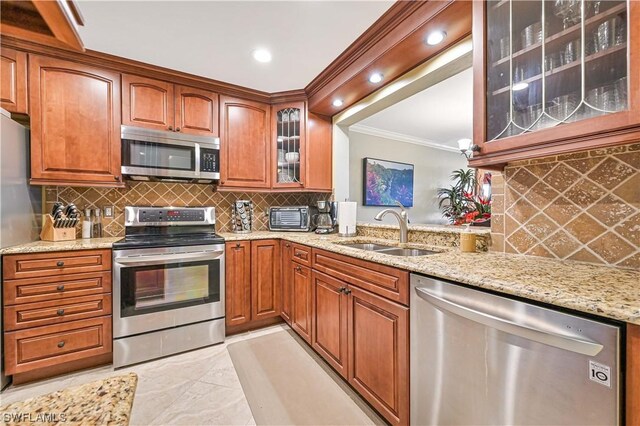 kitchen with tasteful backsplash, light stone countertops, sink, and appliances with stainless steel finishes