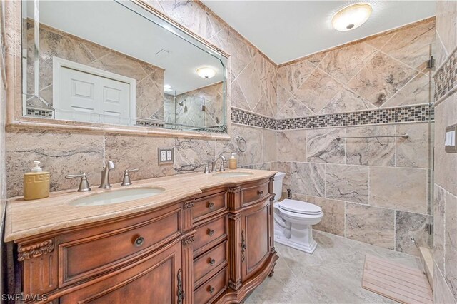 bathroom with a shower with door, vanity, tile walls, and toilet