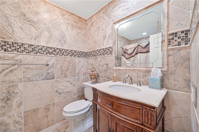 bathroom featuring vanity, toilet, and tile walls