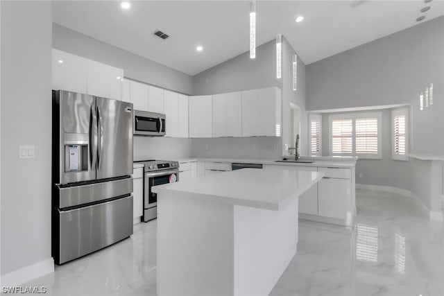 kitchen featuring white cabinets, appliances with stainless steel finishes, light tile floors, and a center island