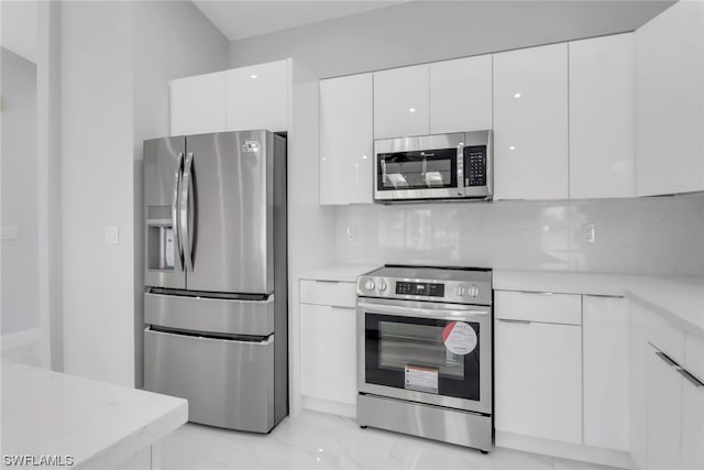 kitchen with white cabinets, light tile flooring, tasteful backsplash, and appliances with stainless steel finishes