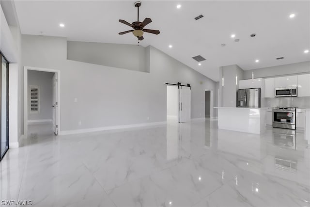 unfurnished living room with high vaulted ceiling, a barn door, and light tile floors