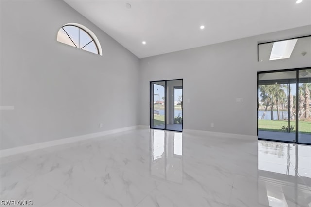 unfurnished room featuring a water view, vaulted ceiling, and light tile floors