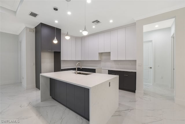 kitchen featuring pendant lighting, light tile flooring, backsplash, a kitchen island with sink, and sink