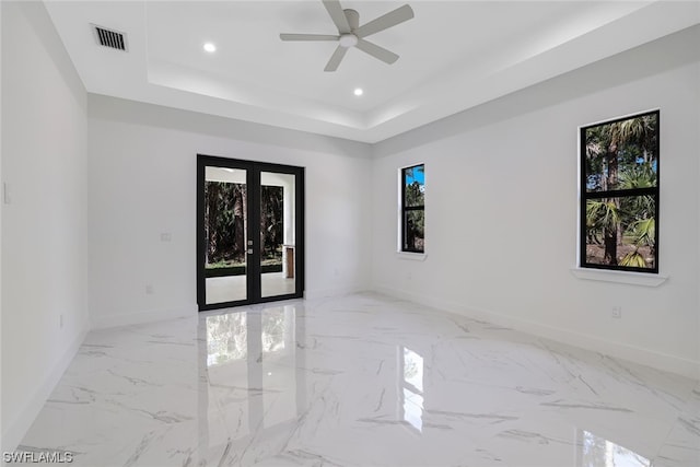 tiled empty room featuring a tray ceiling and ceiling fan