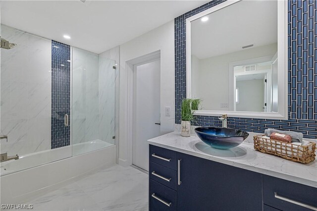 bathroom featuring vanity, combined bath / shower with glass door, and backsplash