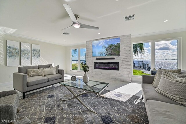 living room with ceiling fan, a large fireplace, and ornamental molding