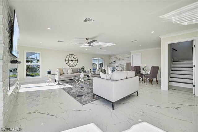 living room with ceiling fan, plenty of natural light, and ornamental molding