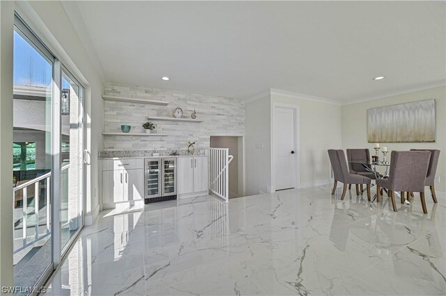 dining room featuring wood walls, ornamental molding, and wine cooler