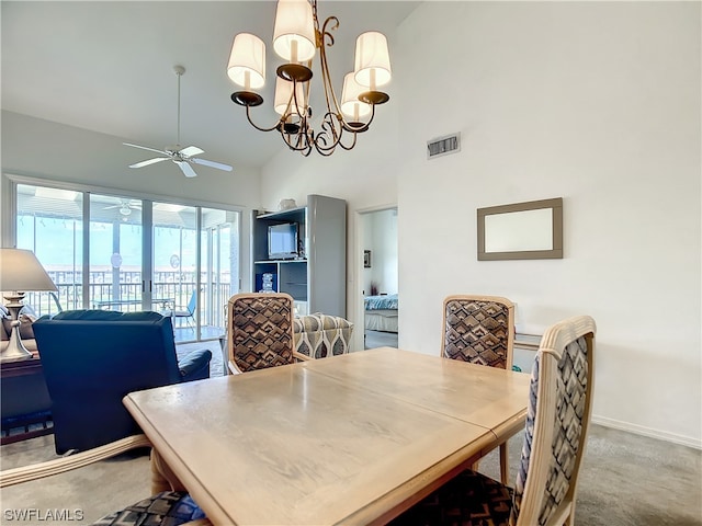 dining space with high vaulted ceiling, ceiling fan with notable chandelier, and light colored carpet