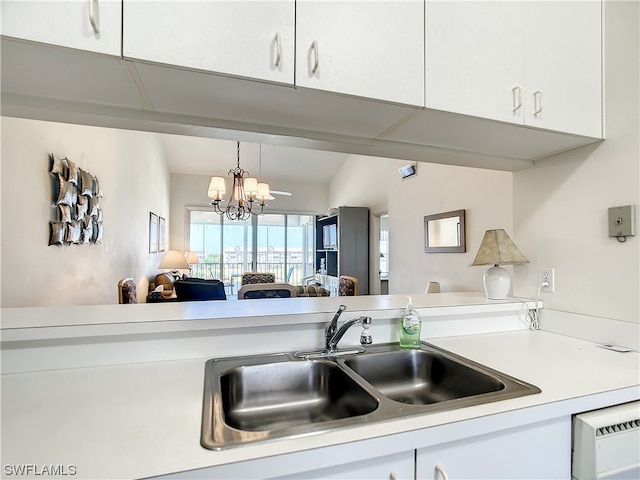 kitchen featuring a chandelier, pendant lighting, white cabinetry, and sink