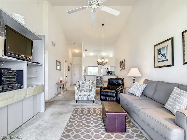 carpeted living room with high vaulted ceiling and ceiling fan with notable chandelier