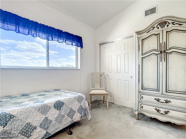 bedroom with a closet, light colored carpet, and lofted ceiling