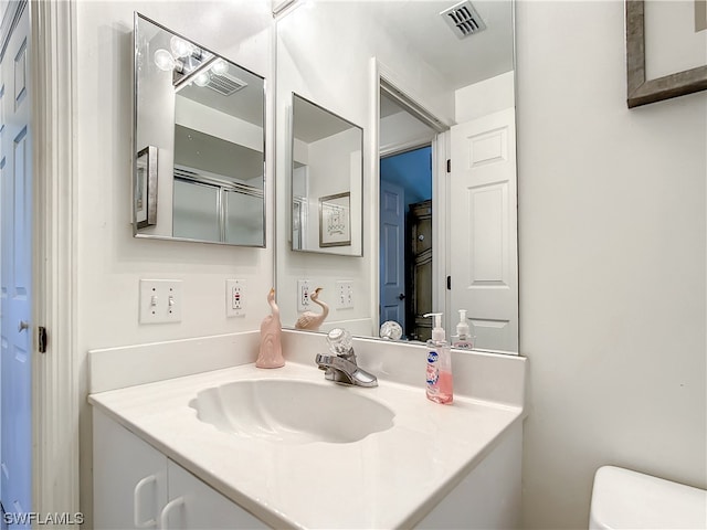 bathroom with toilet and vanity with extensive cabinet space