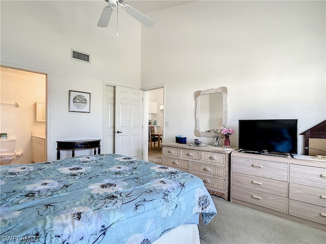 carpeted bedroom with connected bathroom, ceiling fan, and a high ceiling