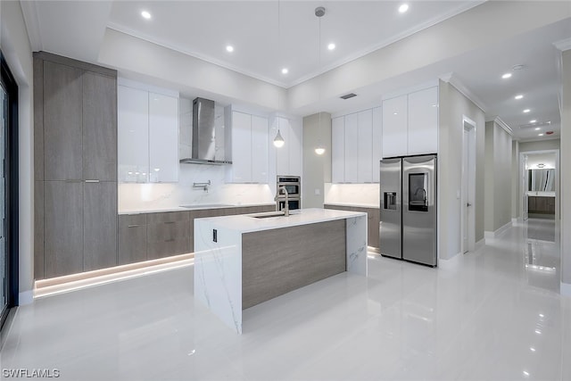 kitchen with pendant lighting, stainless steel appliances, wall chimney exhaust hood, white cabinets, and backsplash