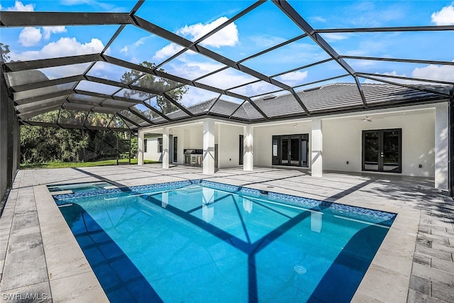 view of pool with a patio area, ceiling fan, and glass enclosure