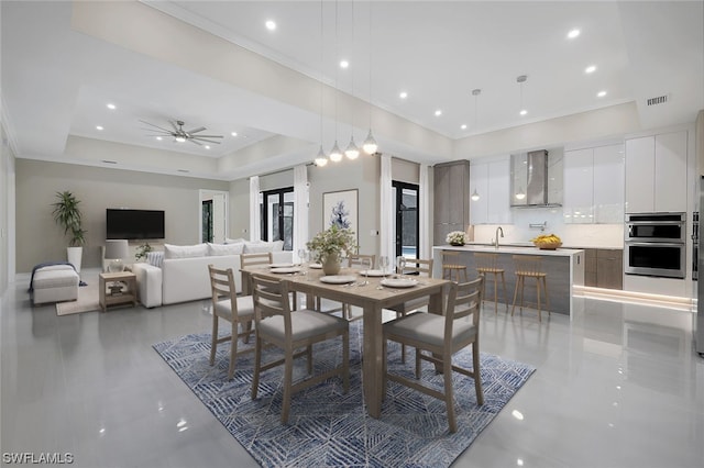 dining room with a tray ceiling, dark tile floors, ceiling fan, and sink