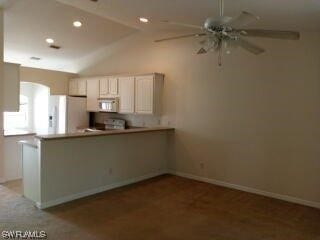 kitchen featuring white appliances, light colored carpet, ceiling fan, and lofted ceiling