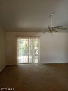 empty room featuring dark colored carpet, ceiling fan, and a wealth of natural light