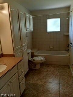 full bathroom with tile floors, tiled shower / bath combo, toilet, and vanity