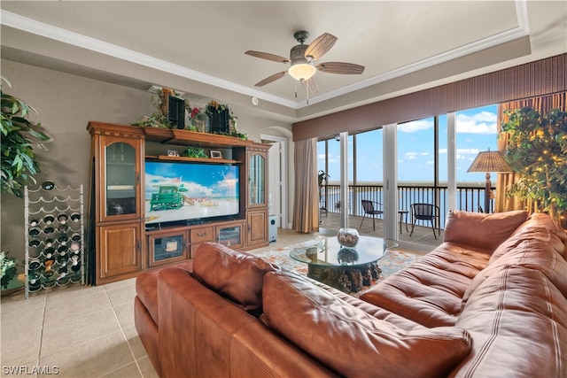 tiled living room with a water view, ornamental molding, and ceiling fan