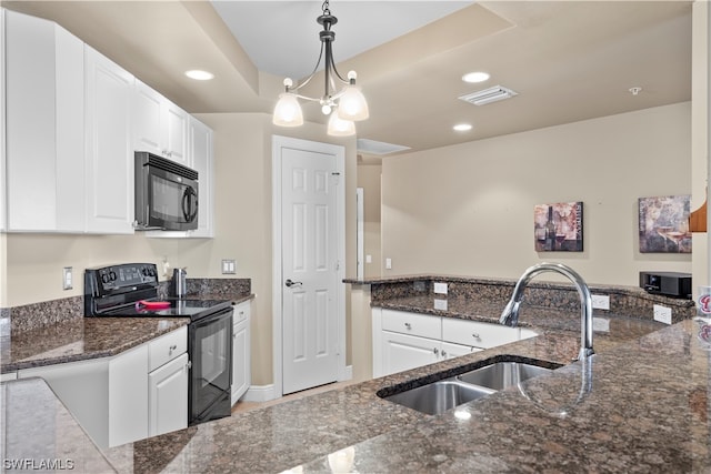 kitchen featuring dark stone countertops, white cabinets, black appliances, decorative light fixtures, and a notable chandelier