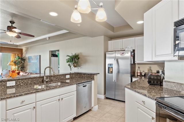 kitchen featuring white cabinetry, ceiling fan with notable chandelier, appliances with stainless steel finishes, and a tray ceiling