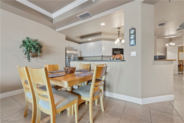 dining space featuring a notable chandelier, a tray ceiling, ornamental molding, and light tile floors