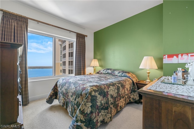 bedroom featuring light colored carpet, multiple windows, and a water view