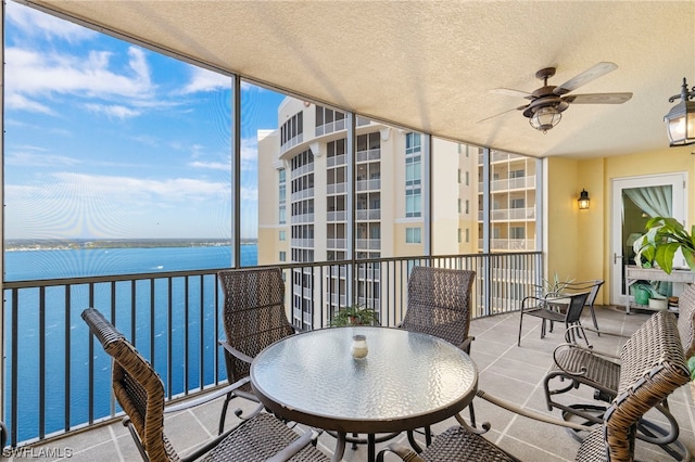 balcony with ceiling fan and a water view