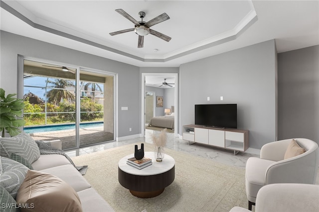 living room with a tray ceiling and ceiling fan