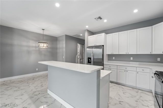 kitchen featuring decorative light fixtures, white cabinetry, an island with sink, and appliances with stainless steel finishes