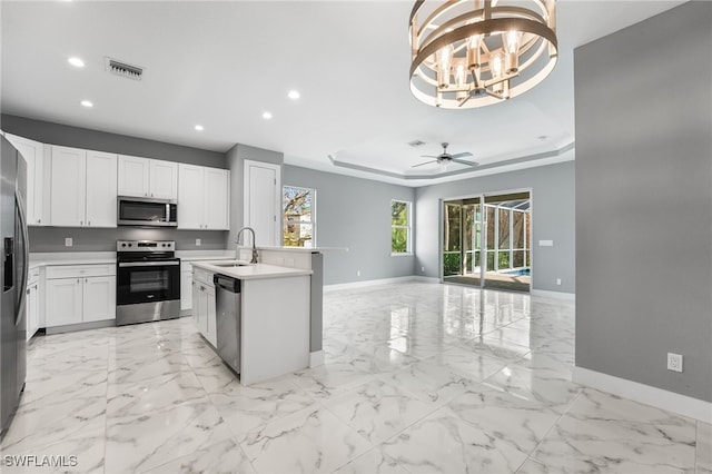 kitchen with sink, white cabinets, ceiling fan with notable chandelier, and appliances with stainless steel finishes