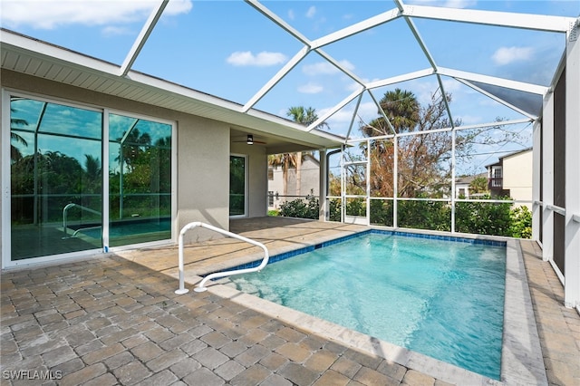 view of swimming pool with glass enclosure, a patio area, and ceiling fan