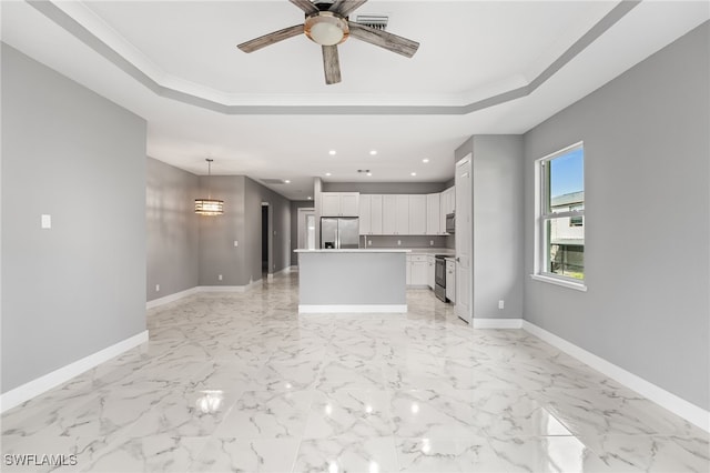 kitchen featuring a center island, a raised ceiling, decorative light fixtures, white cabinets, and appliances with stainless steel finishes