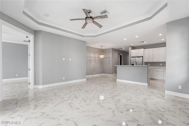 unfurnished living room with a raised ceiling, ceiling fan, and crown molding