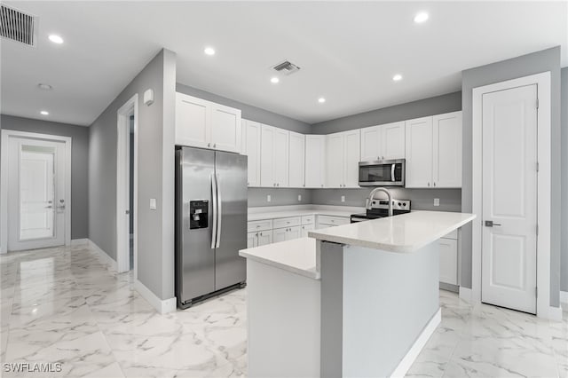 kitchen with white cabinets, a kitchen island with sink, and appliances with stainless steel finishes