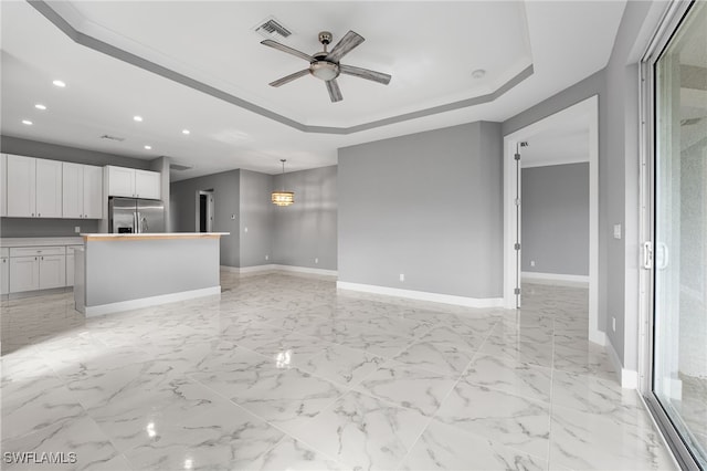 unfurnished living room with a raised ceiling and ceiling fan