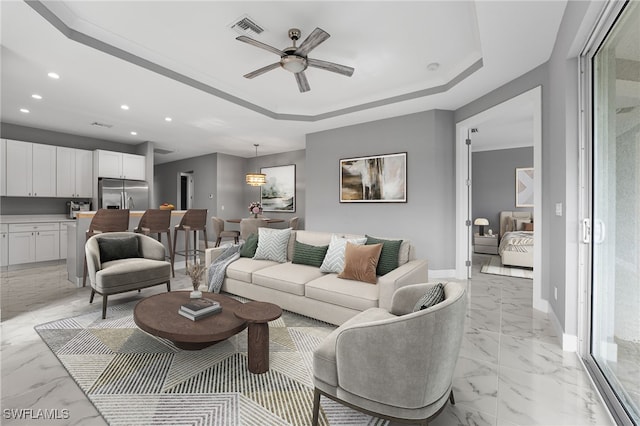 living room featuring ceiling fan and a tray ceiling