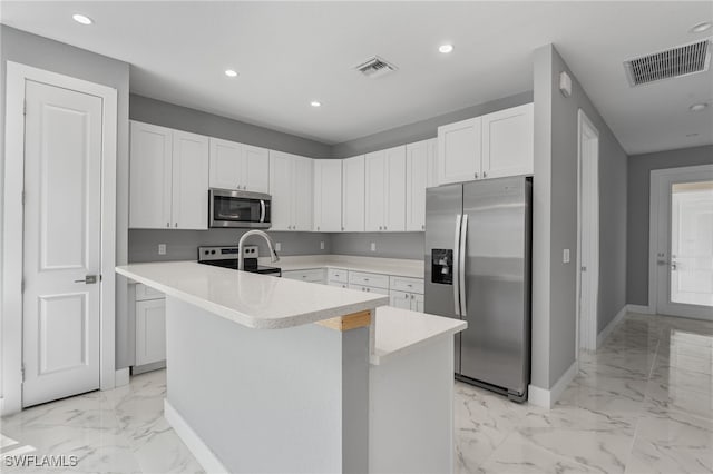 kitchen with appliances with stainless steel finishes, white cabinetry, and an island with sink