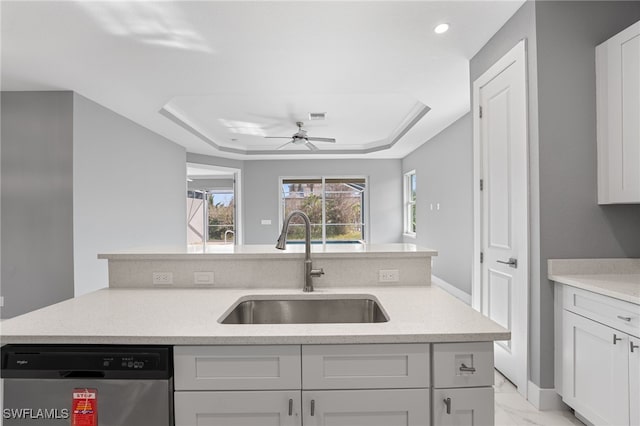 kitchen with stainless steel dishwasher, ceiling fan, a raised ceiling, and sink