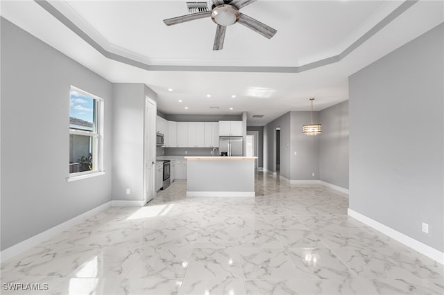 kitchen with a center island, ceiling fan, appliances with stainless steel finishes, decorative light fixtures, and white cabinetry