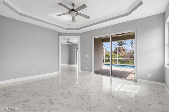 unfurnished room with ceiling fan and a raised ceiling