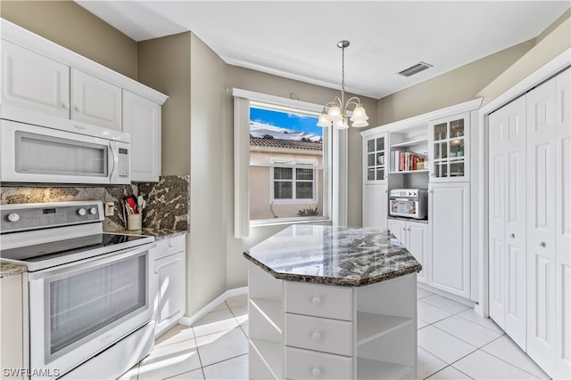 kitchen with white appliances, light tile patterned floors, a notable chandelier, a kitchen island, and white cabinetry