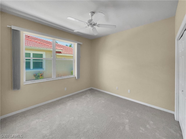 empty room featuring ceiling fan and light colored carpet