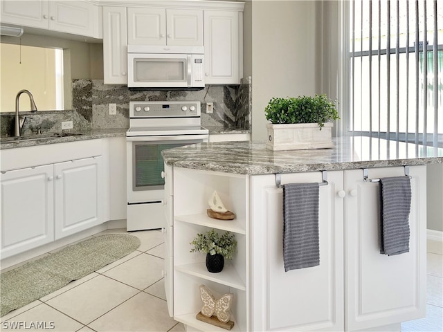 kitchen with white cabinetry, sink, light stone countertops, white appliances, and light tile patterned floors