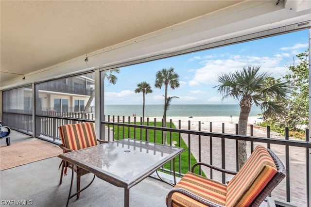 sunroom with a water view and a view of the beach